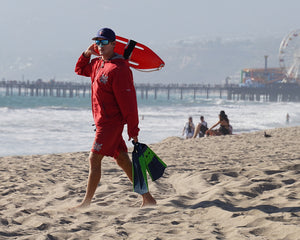 Prepared Lifeguard on the beach while protecting his nose with colorful reef safe SPF sunscreen, Nöz.